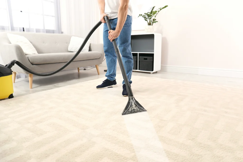 Technician using professional carpet extraction equipment on a carpeted floor